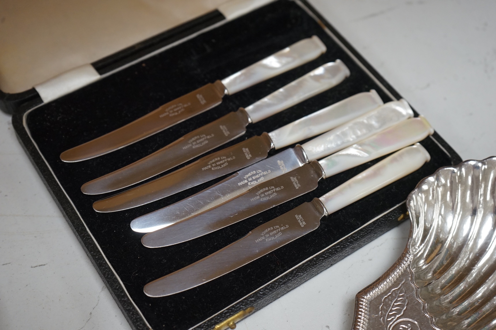 A Mappin plated muffin dish and six other plated items including three Old Sheffield plate butter shells, a wine funnel, Elkington & Co cream jug and cased set of tea knives.